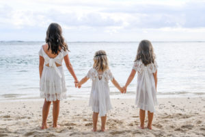 The three flower girls hold hands as they overlook the Pacific Ocean at Shangri La Beach